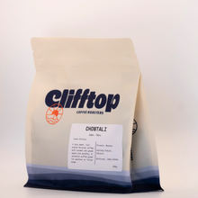 Load image into Gallery viewer, A stand-up coffee bag from Clifftop Coffee Roasters on a plain light background. The bag is cream with a blue-to-silver gradient at the bottom and a white label reading CHONTALI.